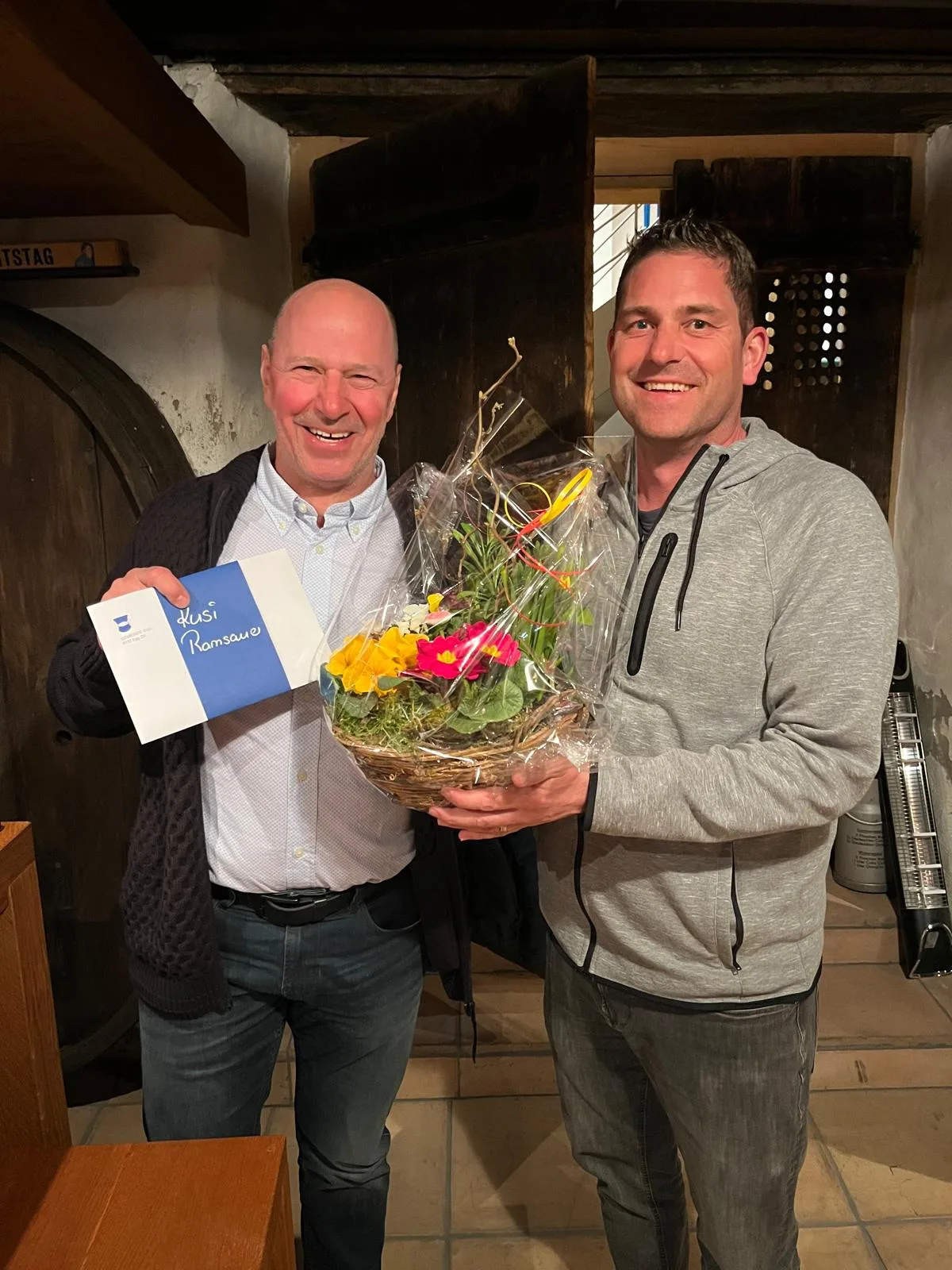 Ein Mann überreicht einem anderen Mann Blumen.